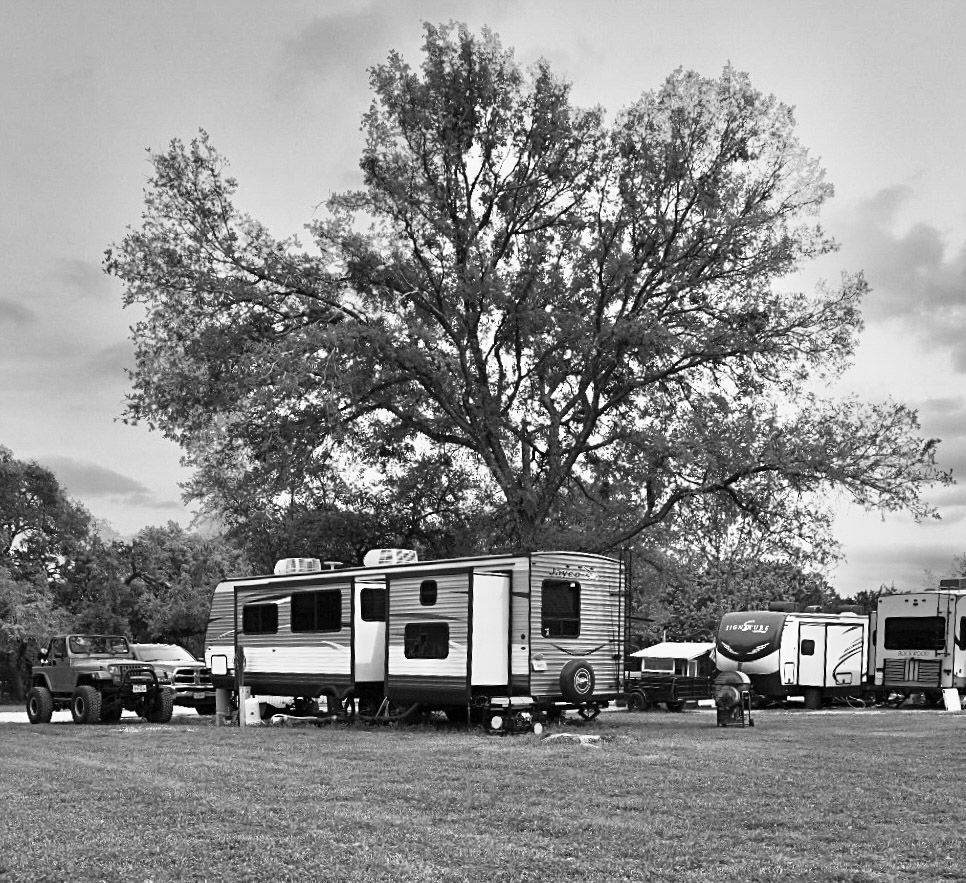A black and white photo of several rvs parked in a field