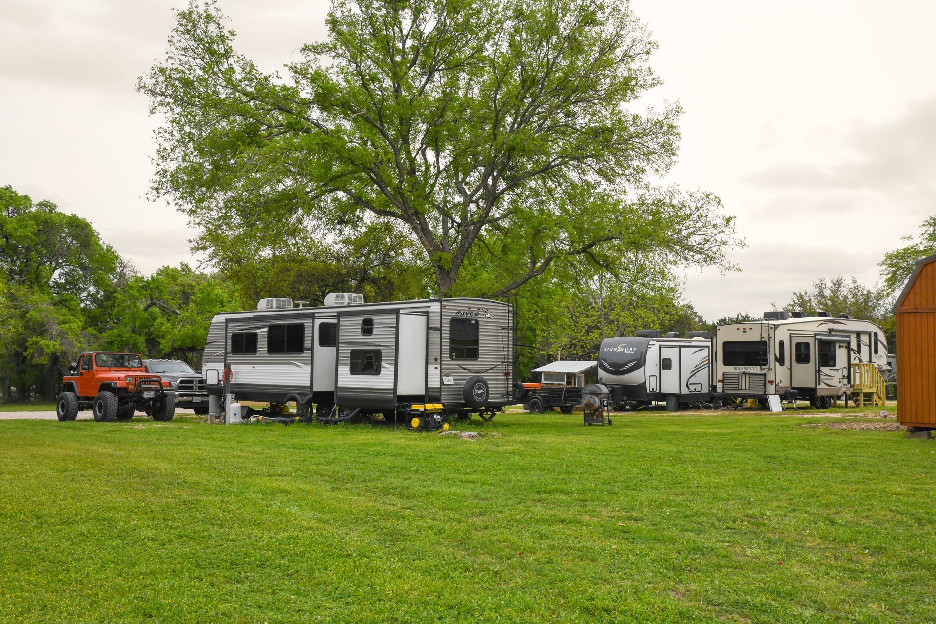A row of rvs are parked in a grassy field.