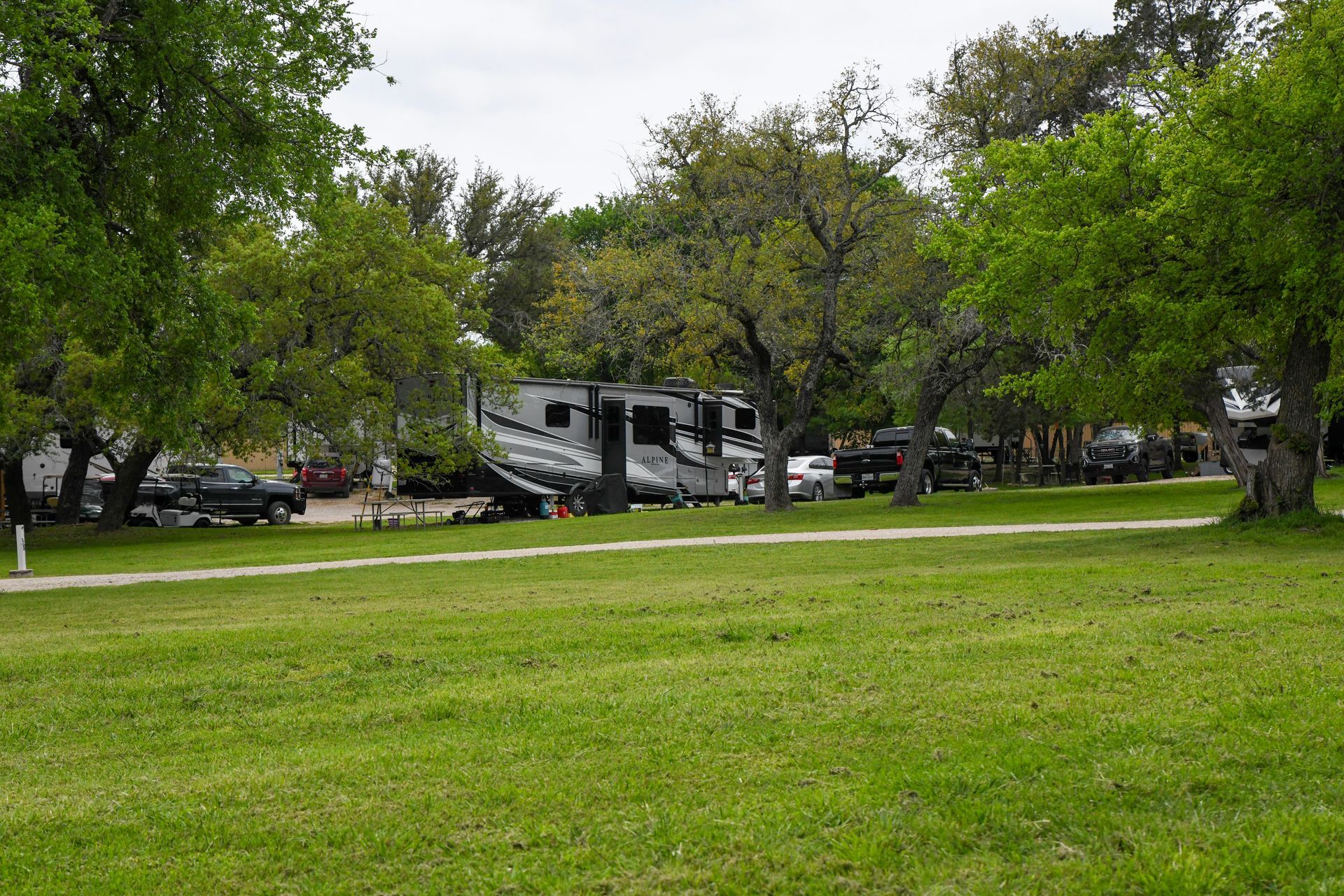 A rv parked in a grassy field surrounded by trees.