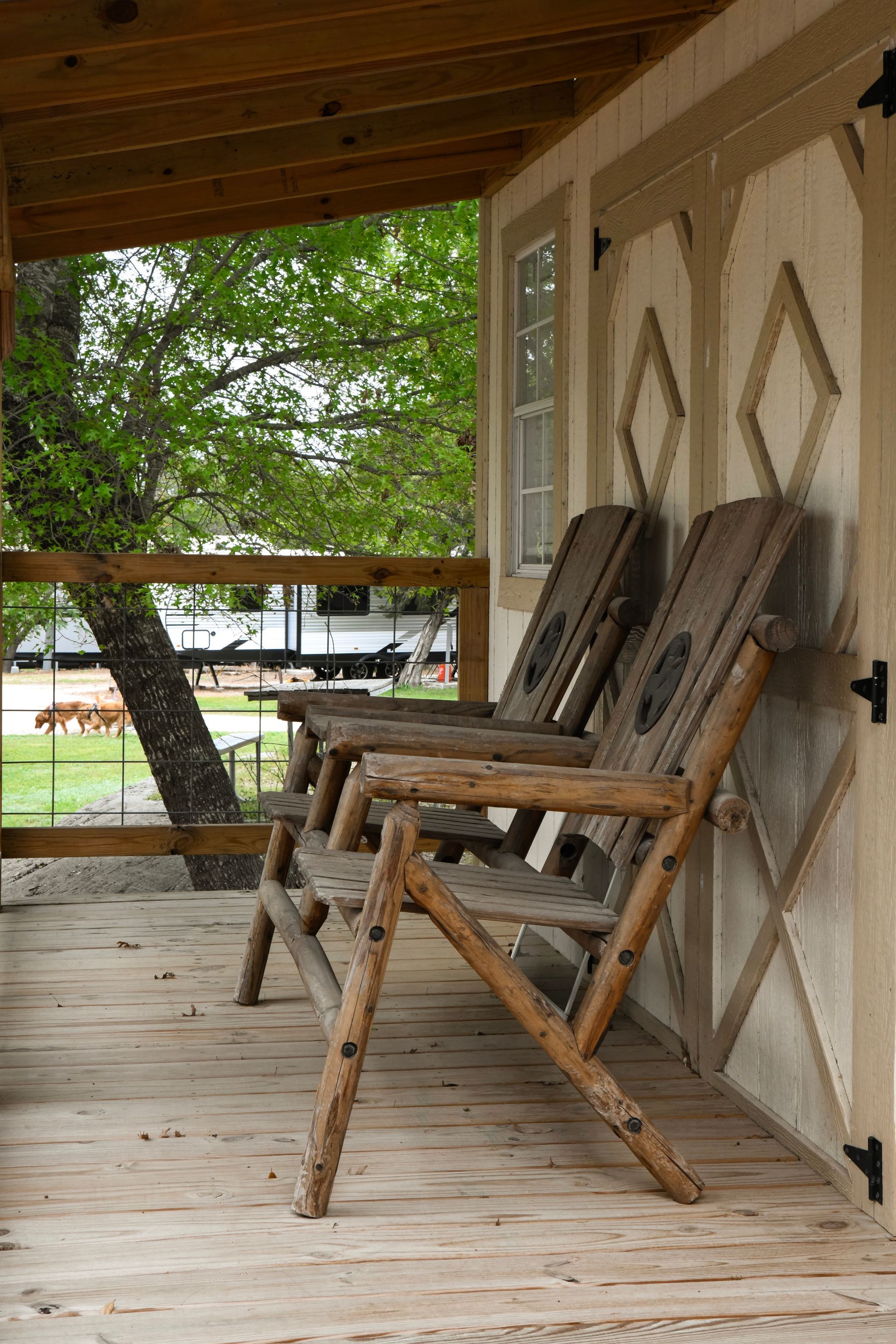 Two wooden chairs are sitting on a wooden porch.