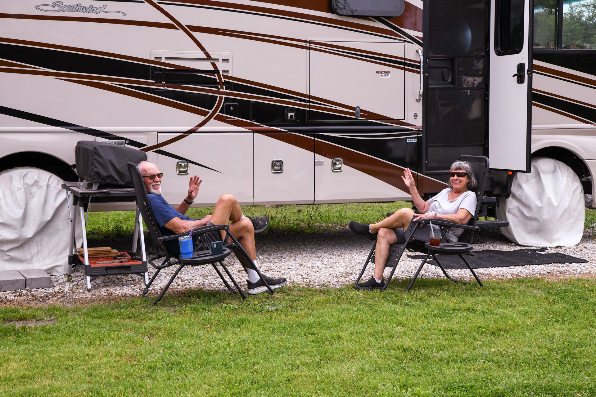 A man and a woman are sitting in chairs in front of a rv.
