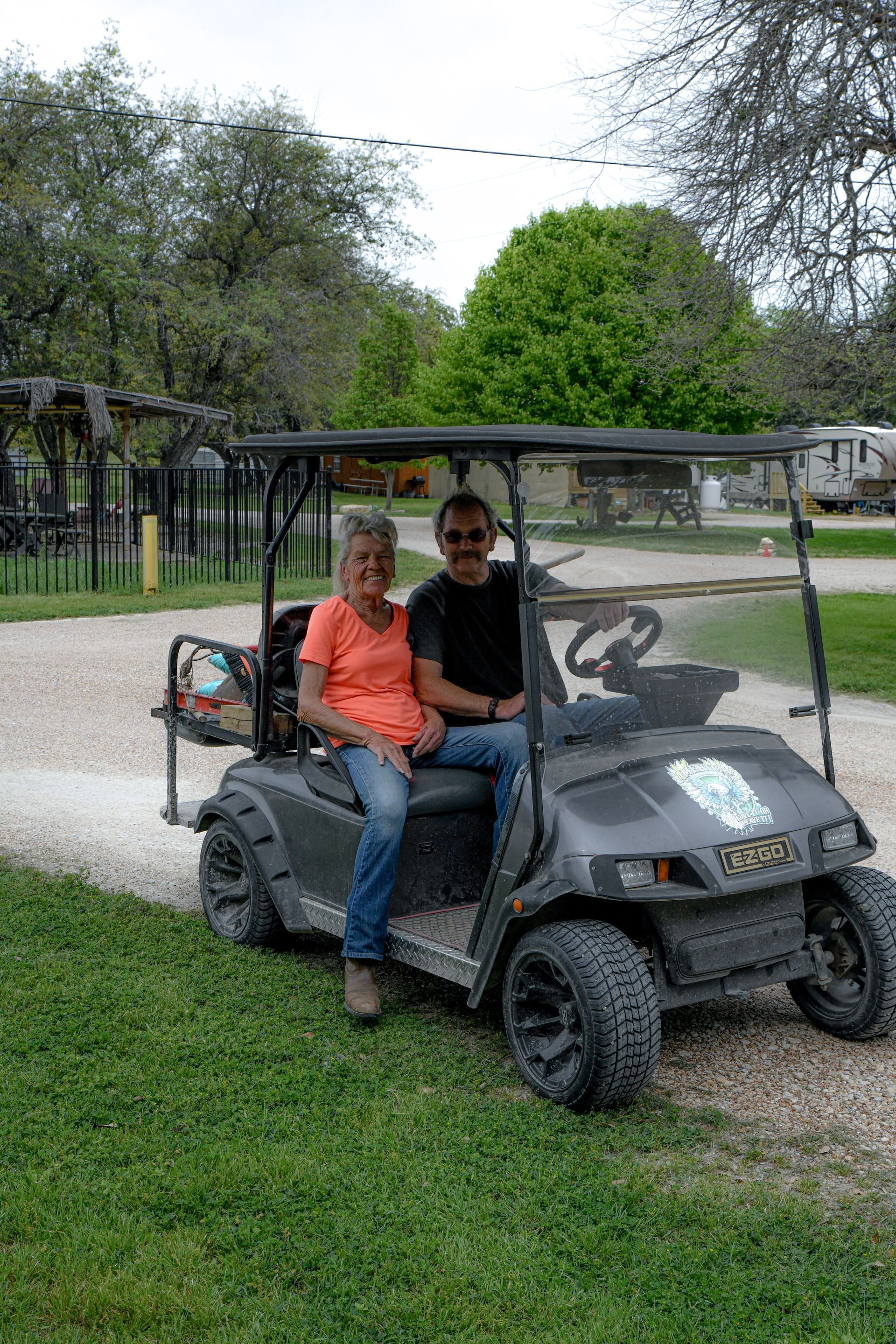 A man and a woman are sitting in a golf cart.