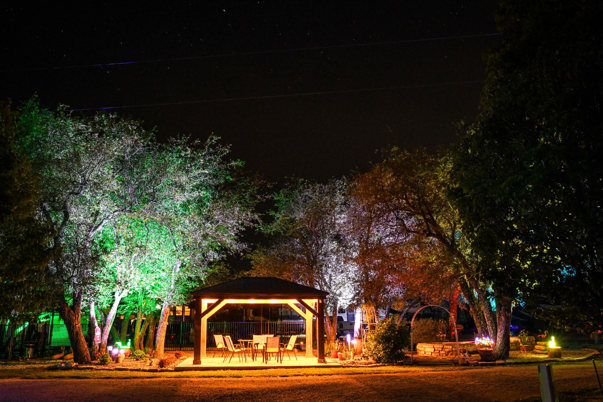 A gazebo is lit up at night in the middle of a forest.