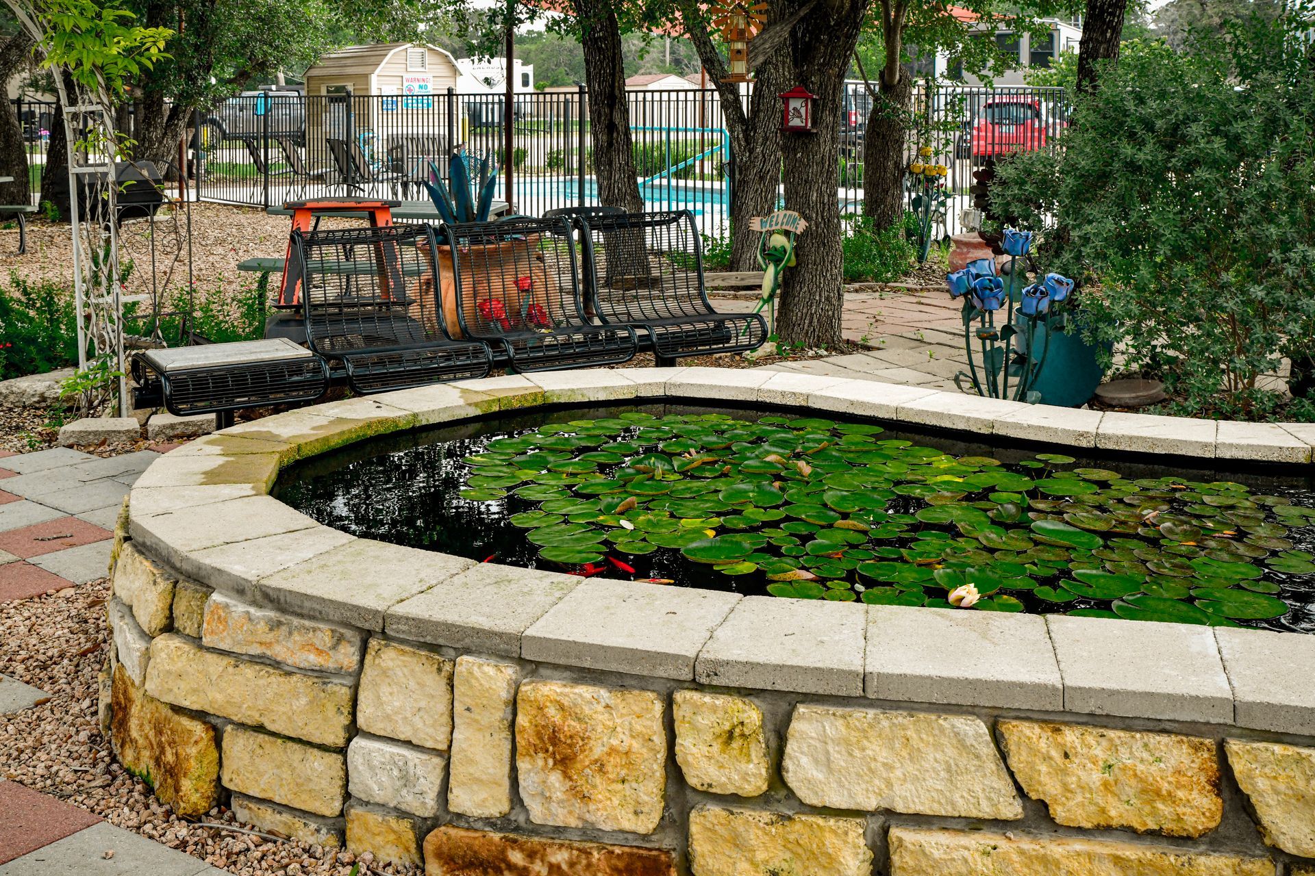 A pond with lily pads in it is surrounded by a stone wall.