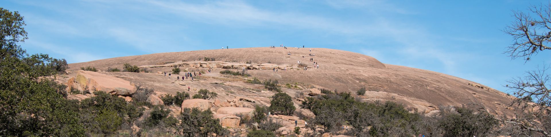A mountain with trees on it and a blue sky in the background.