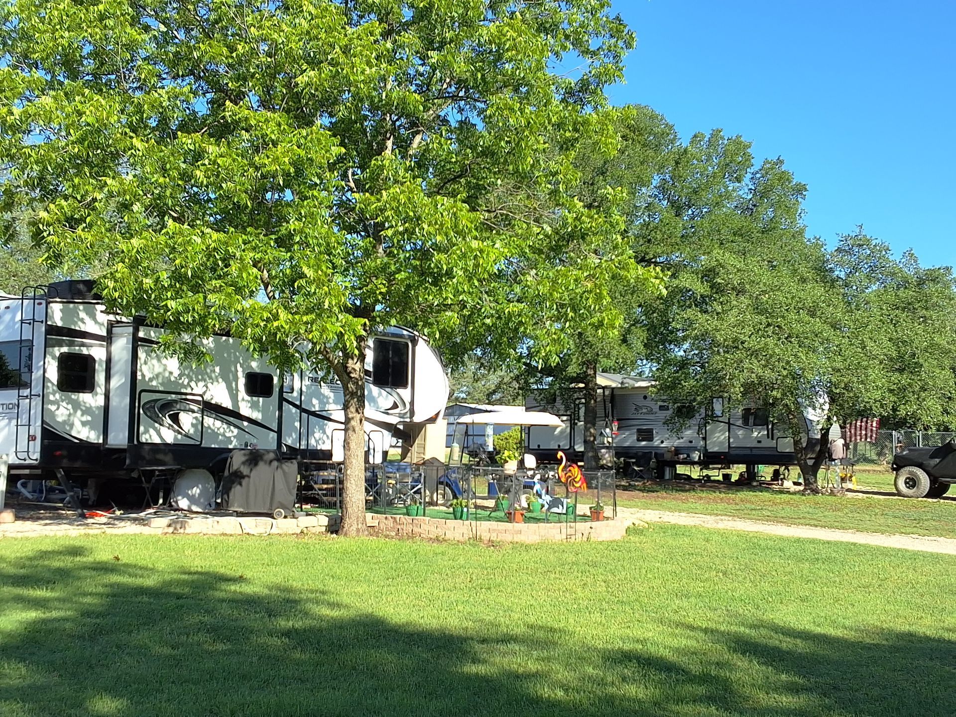 A rv is parked in a grassy field next to trees.
