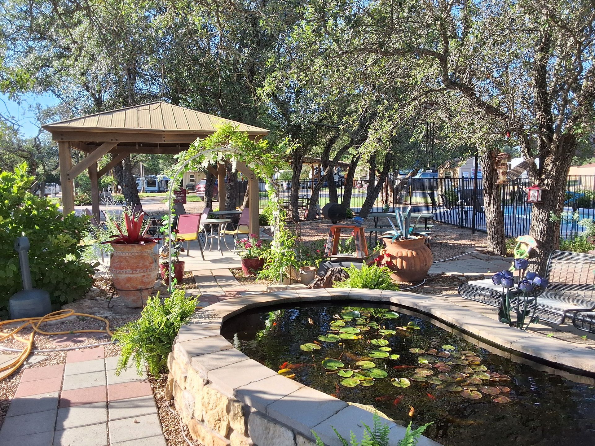 There is a pond in the middle of the garden with a gazebo in the background.