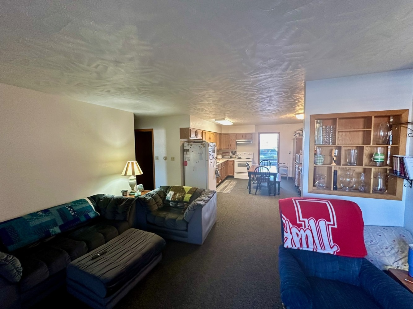 Living room with a sectional sofa, a table, and a view into the kitchen.
