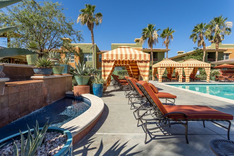 A large swimming pool surrounded by lawn chairs and umbrellas