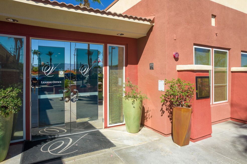 A red building with a glass door and potted plants in front of it