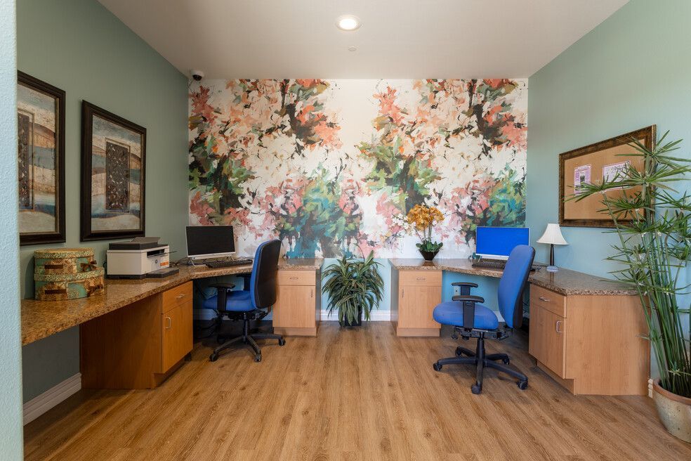 There is a floral wallpaper on the wall in the office.