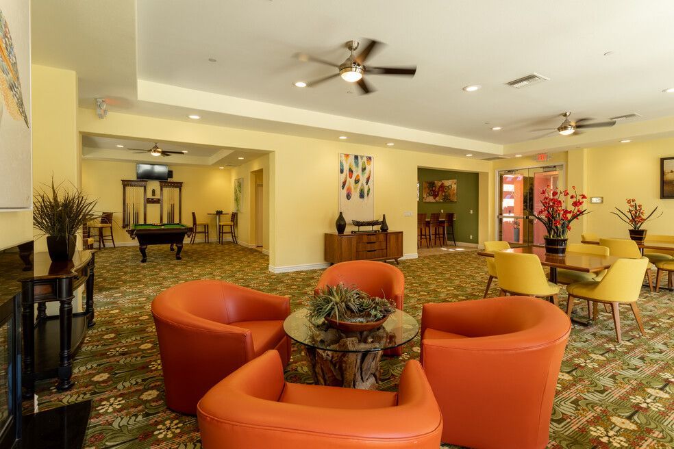A living room with orange chairs and a pool table.