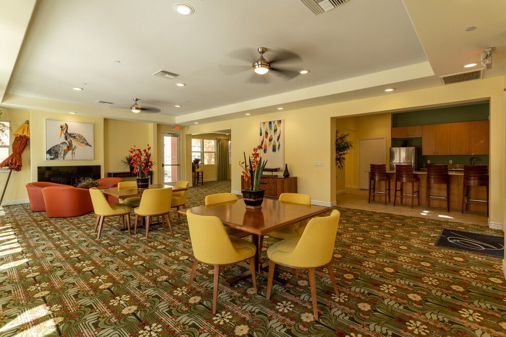 A large room with tables and chairs and a ceiling fan.
