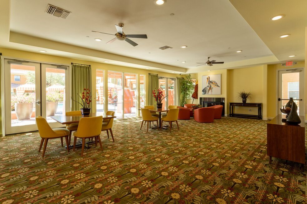 A large room with tables and chairs in it and a ceiling fan.