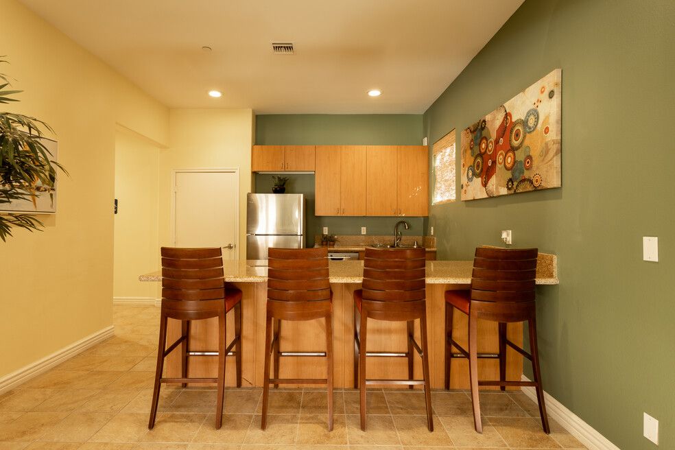 A kitchen with wooden cabinets and a stainless steel refrigerator