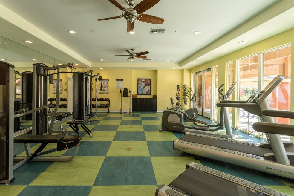 A large gym with a lot of equipment and a ceiling fan.