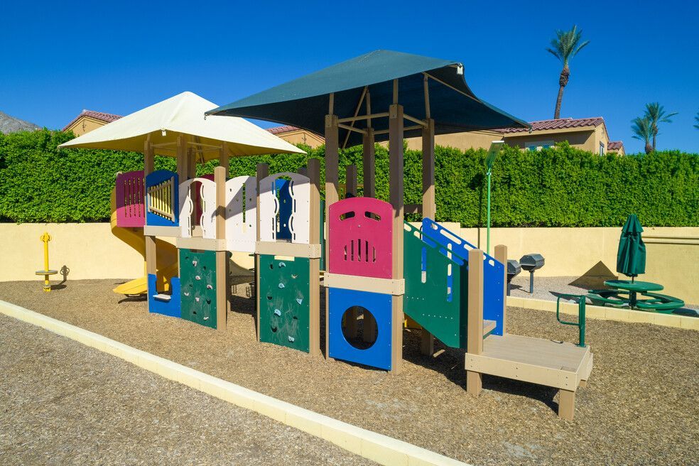 A colorful playground with umbrellas and a fence in the background