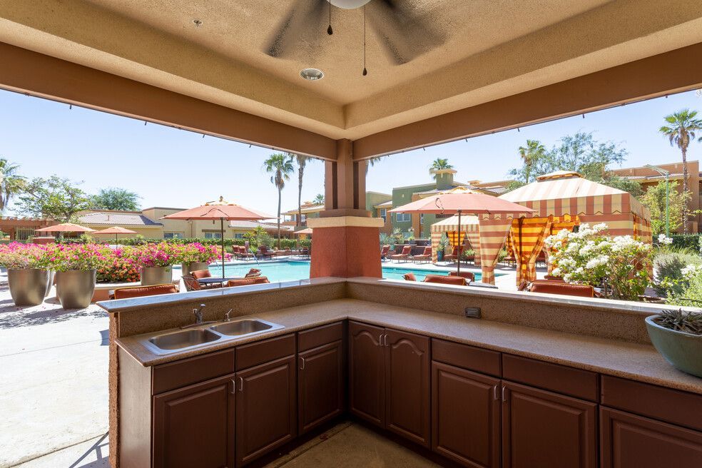 A kitchen with a sink and a ceiling fan overlooking a pool.
