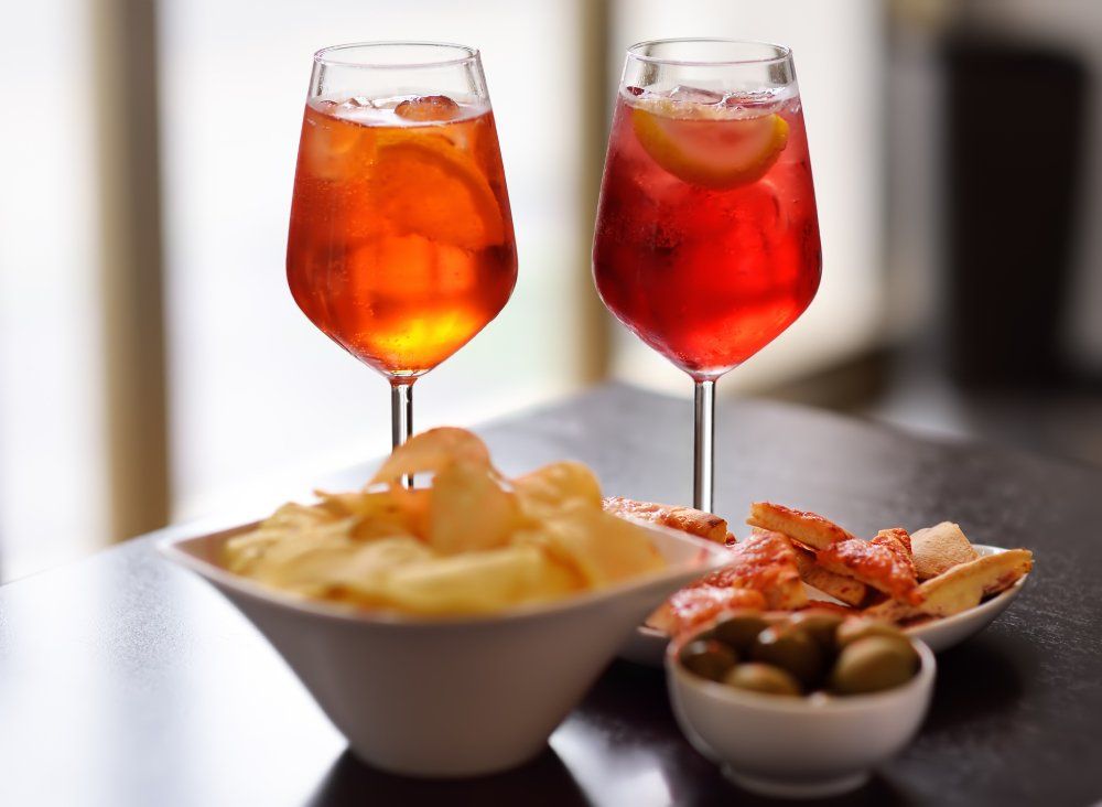 aperitivo con due drink, patatine, olive e pizzette
