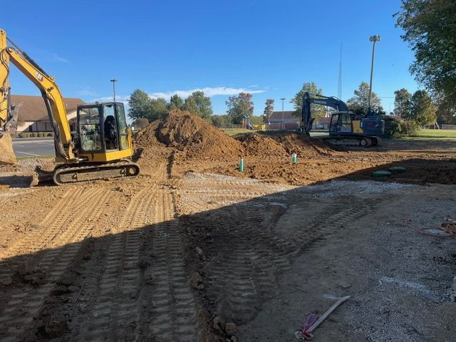 A yellow excavator is sitting on top of a pile of gravel.