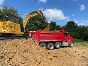 A yellow excavator is sitting on top of a pile of gravel.