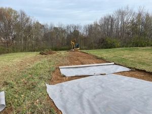 A construction site with a bulldozer and a man standing in the dirt.