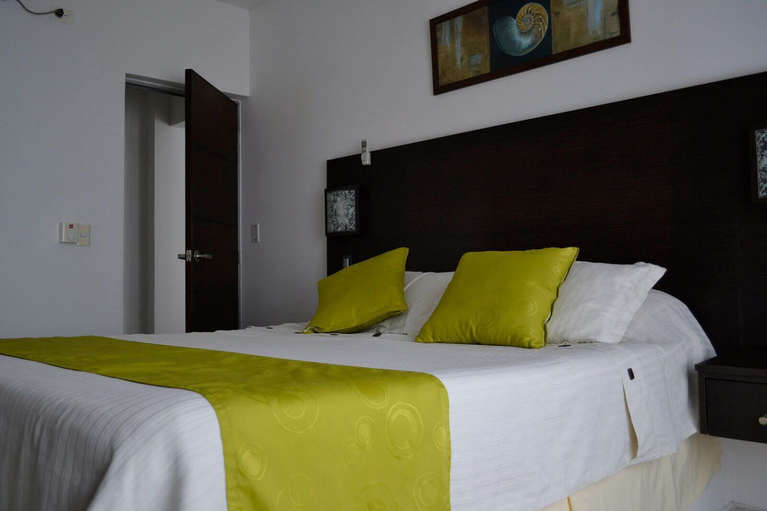 Cama bien hecha con detalles en verde lima en una habitación de hotel moderna.