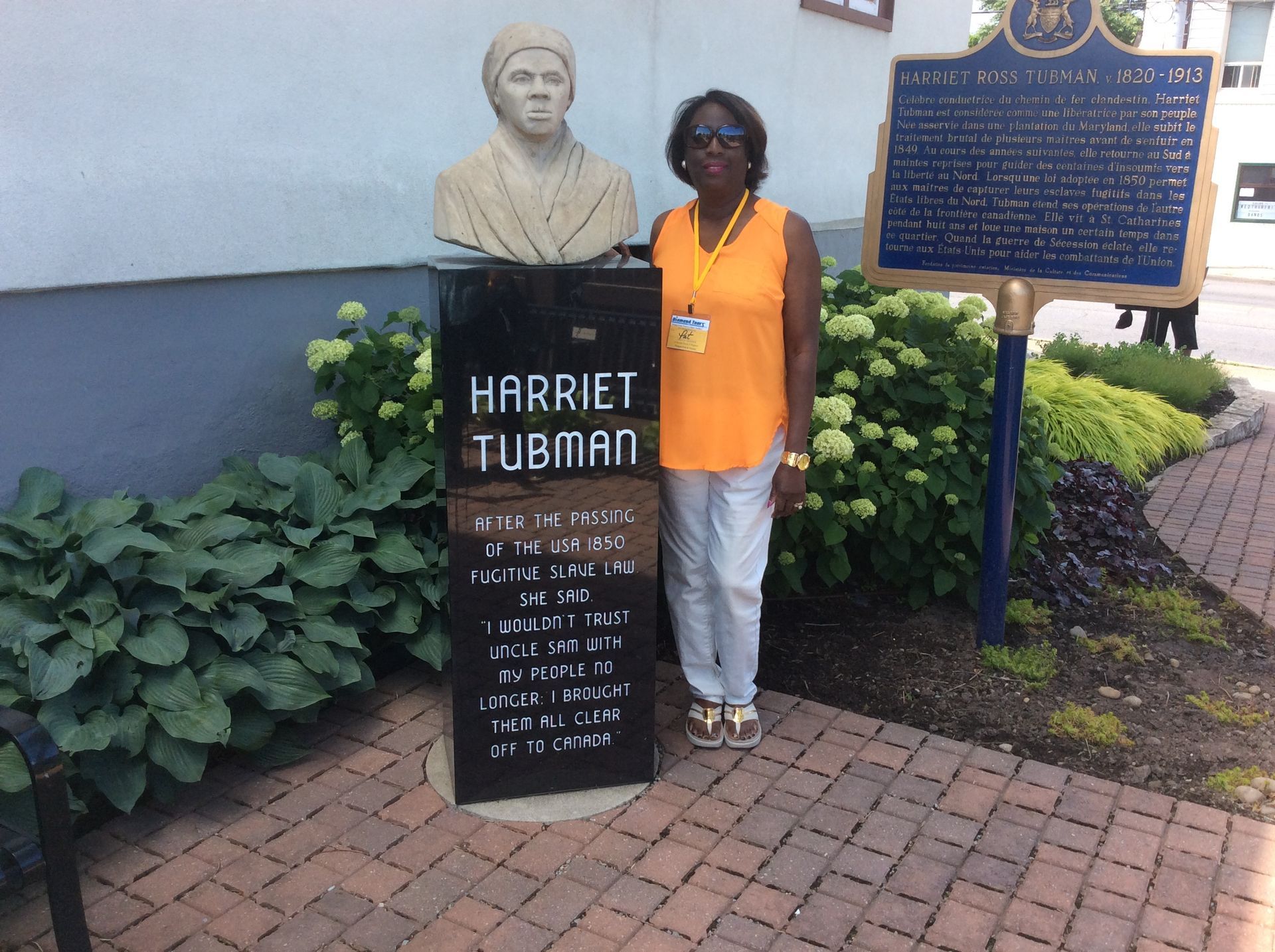 Woman in orange shirt stands by Harriet Tubman historical marker.