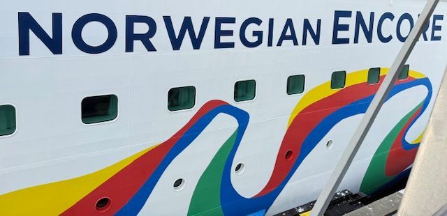 Side of the Norwegian Encore cruise ship with colorful wave design.