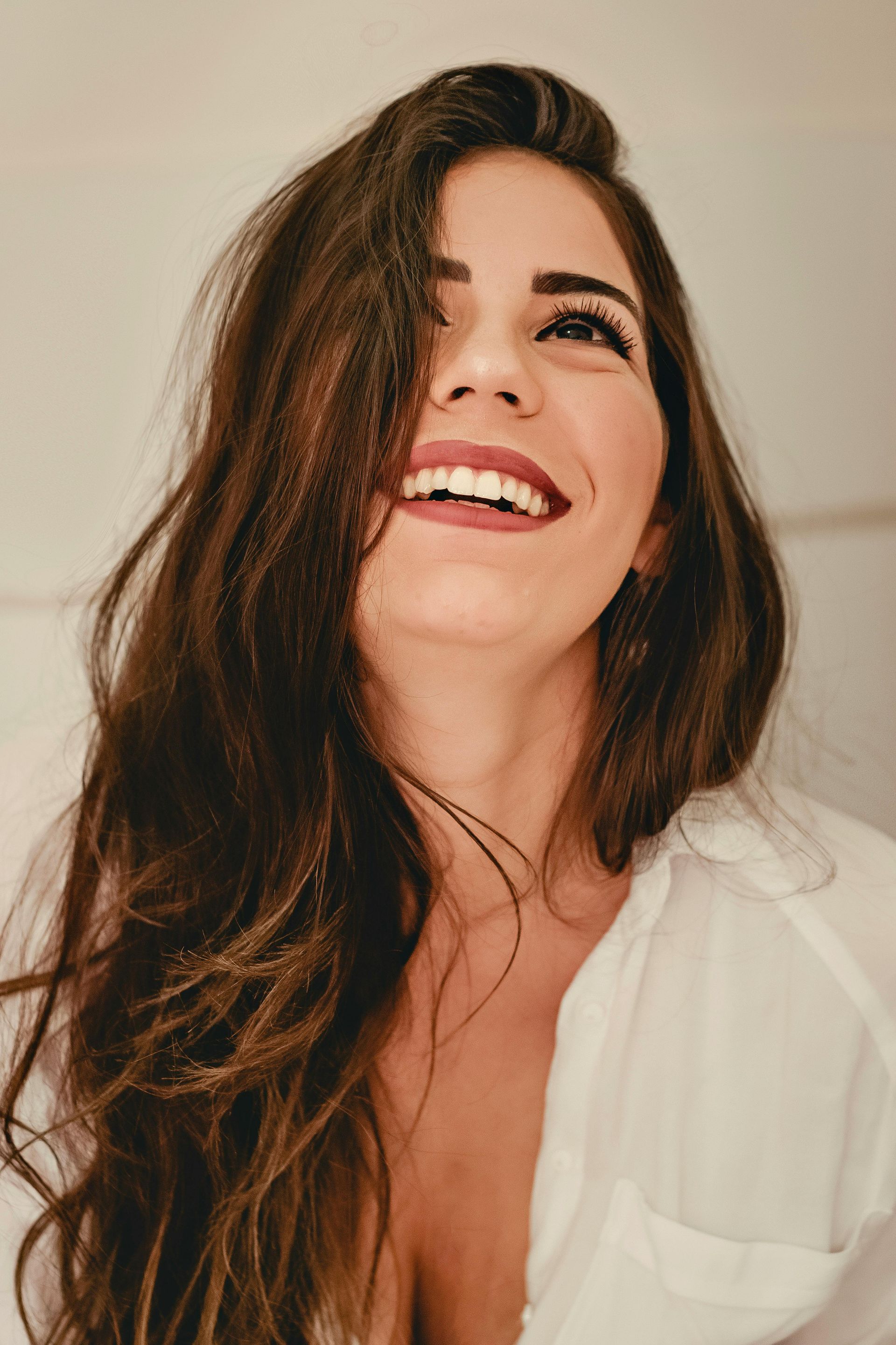 A woman in a white shirt looking up smiling.