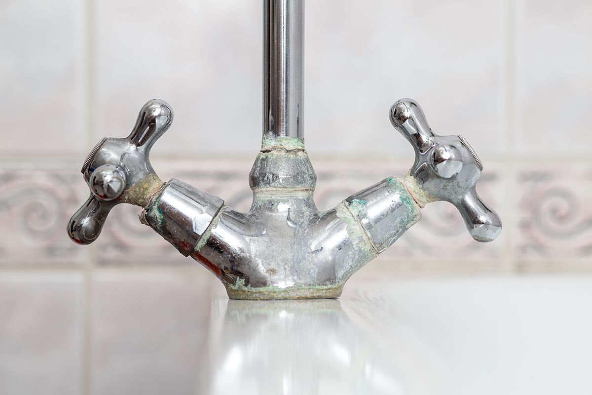 A close up of a dirty faucet in a bathroom.