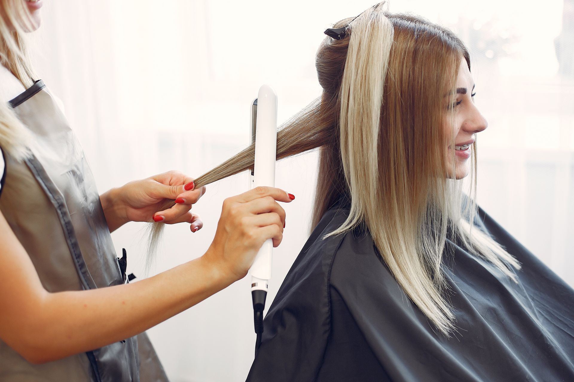 a woman is getting her hair straightened by a hairdresser in a salon