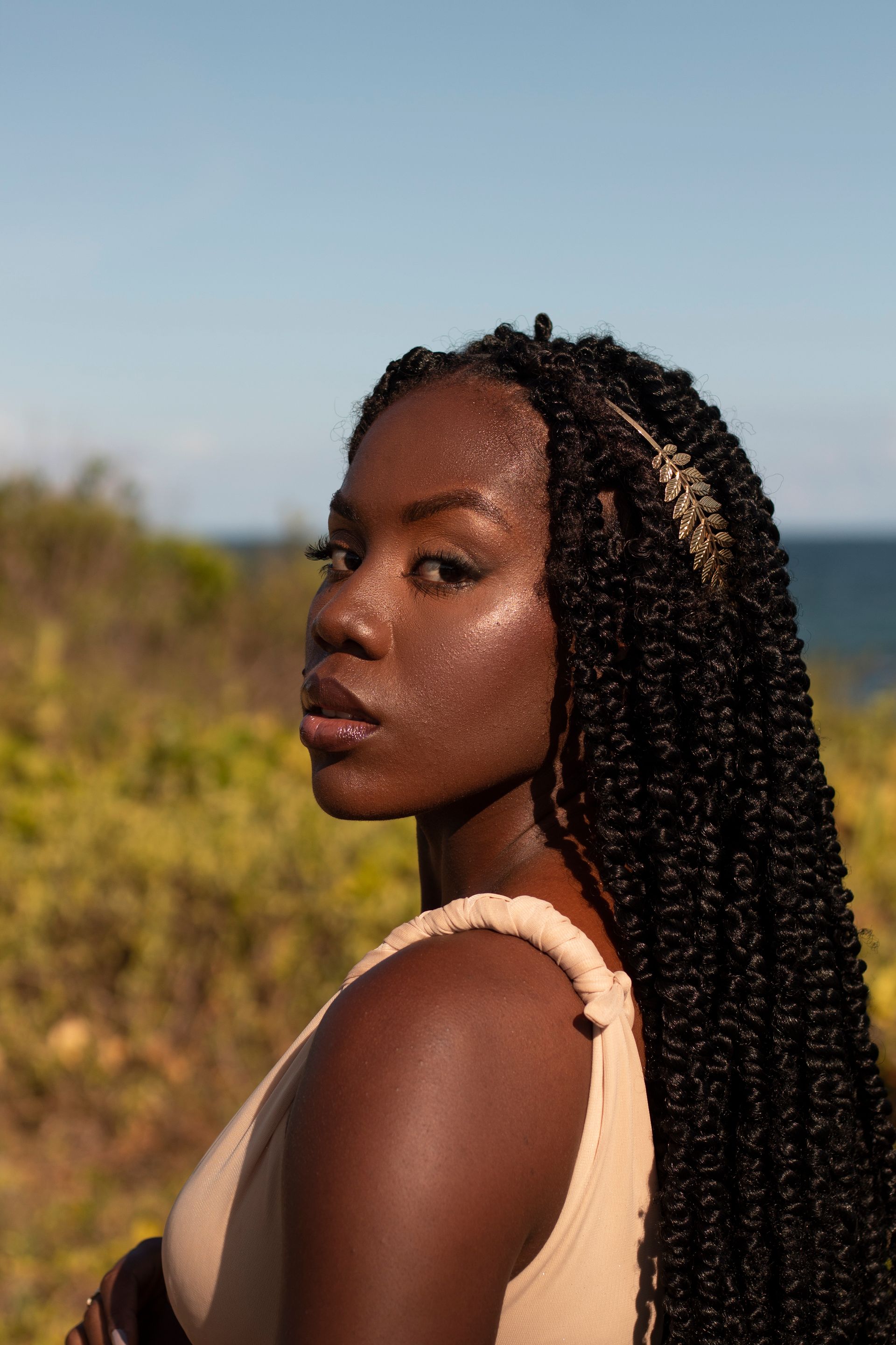 a woman with braids is standing in front of a body of water 