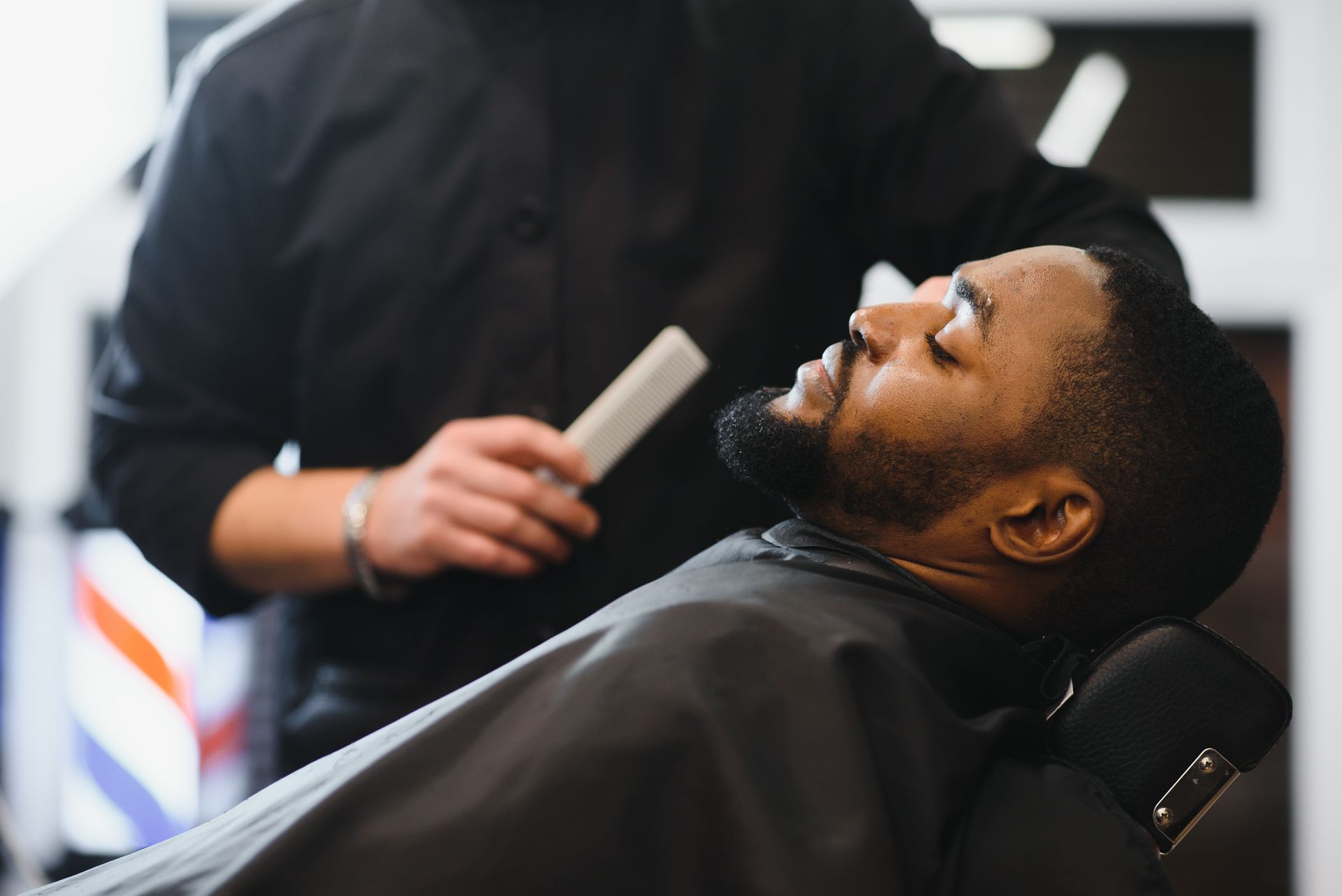 a man is getting his beard shaved by a barber in a barber shop