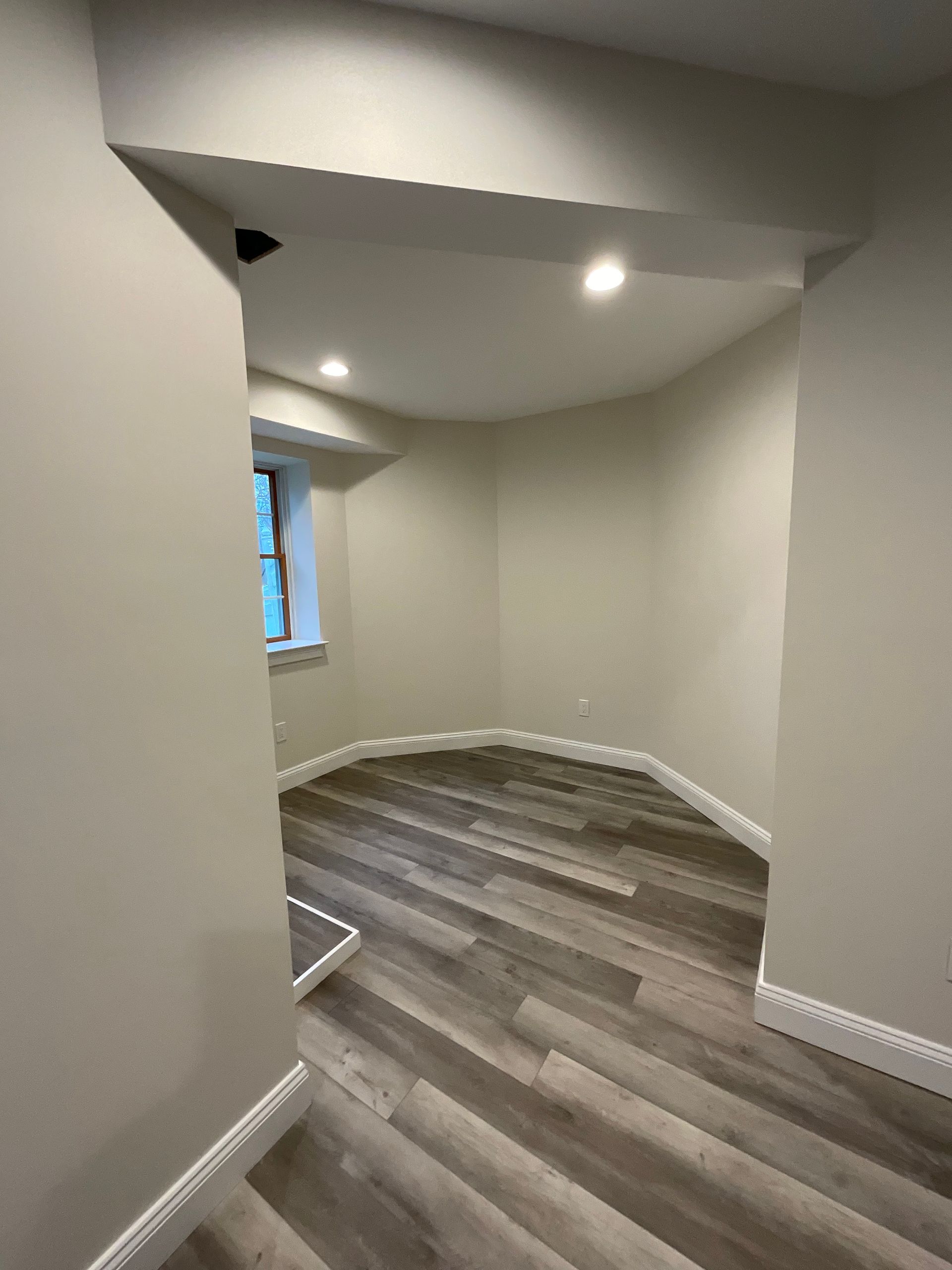 An empty room with a wooden floor and white walls.