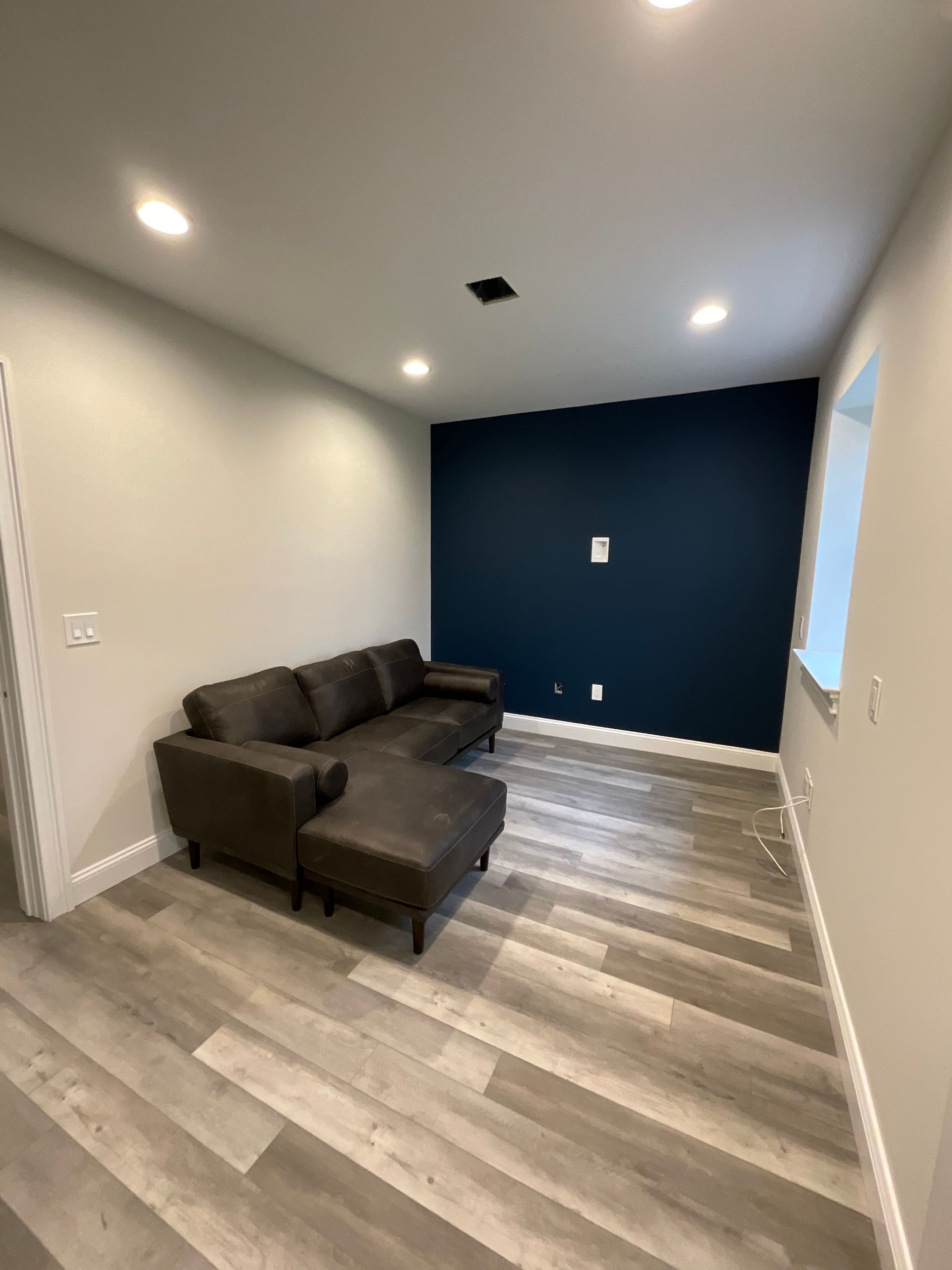 A living room with a couch , ottoman , and blue wall.