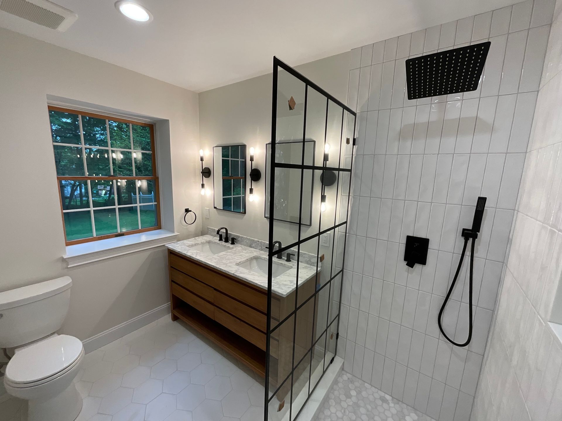 A bathroom with two sinks , a toilet , and a walk in shower.