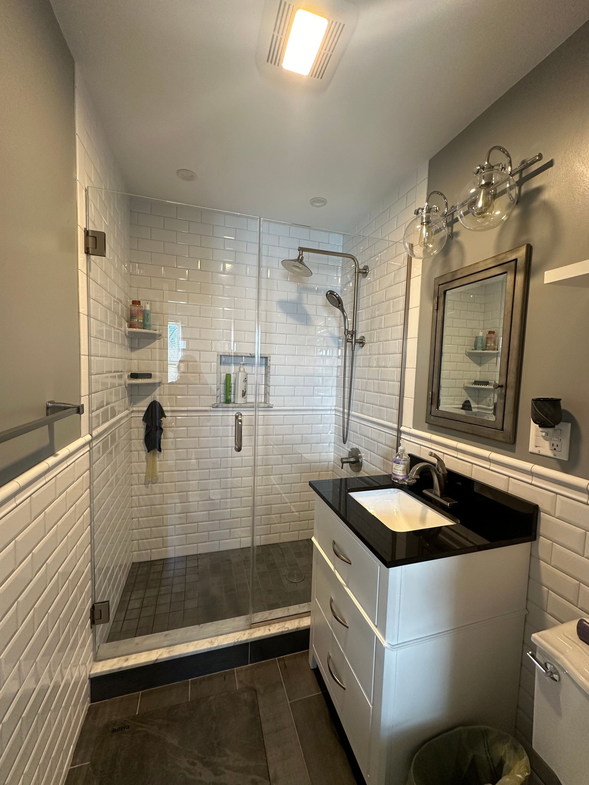 A bathroom with a sink , toilet , shower and mirror.