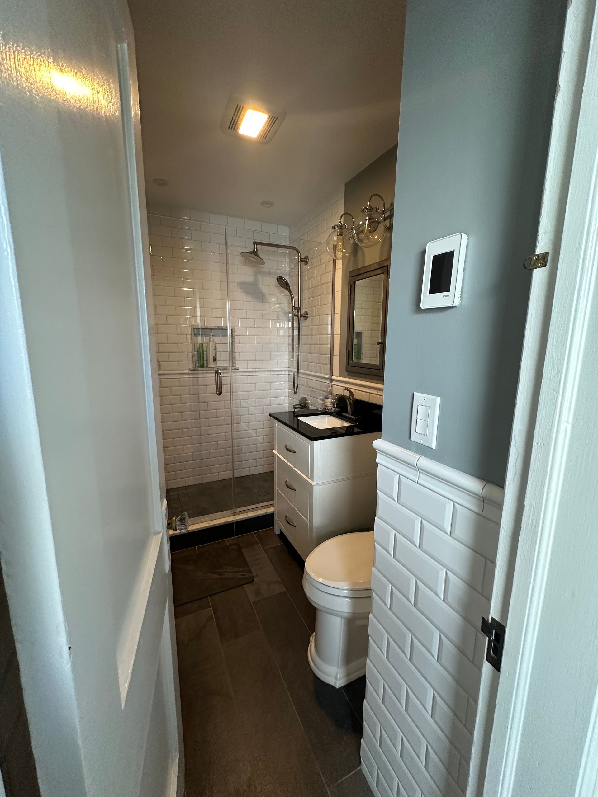 A bathroom with a toilet , sink , shower and mirror.