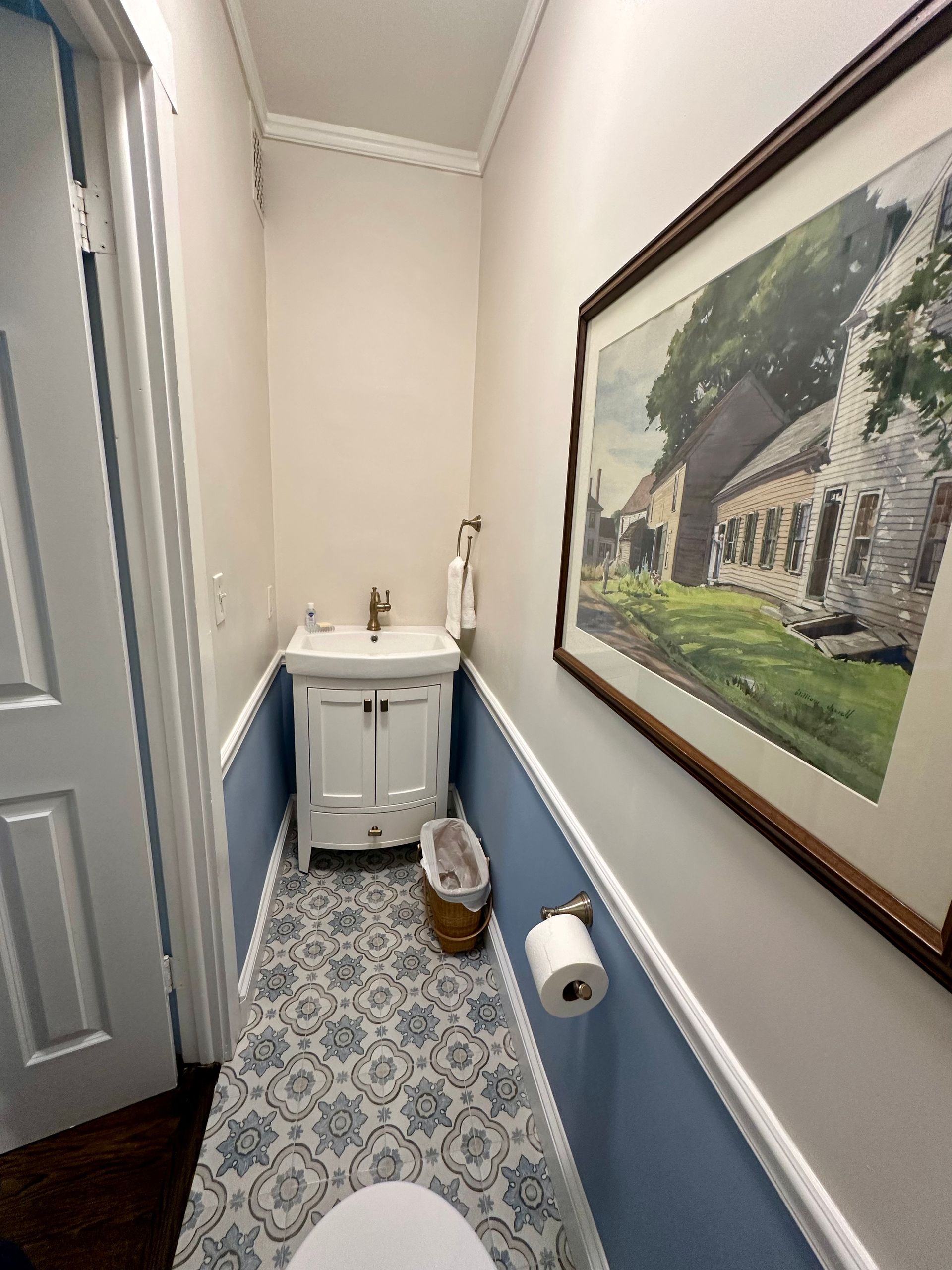 A bathroom with a sink , toilet and a picture on the wall.