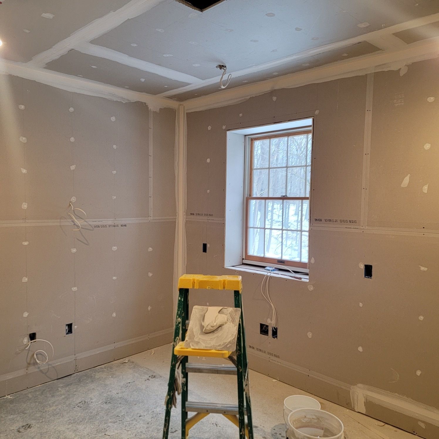 A room with a window and a ladder in it.