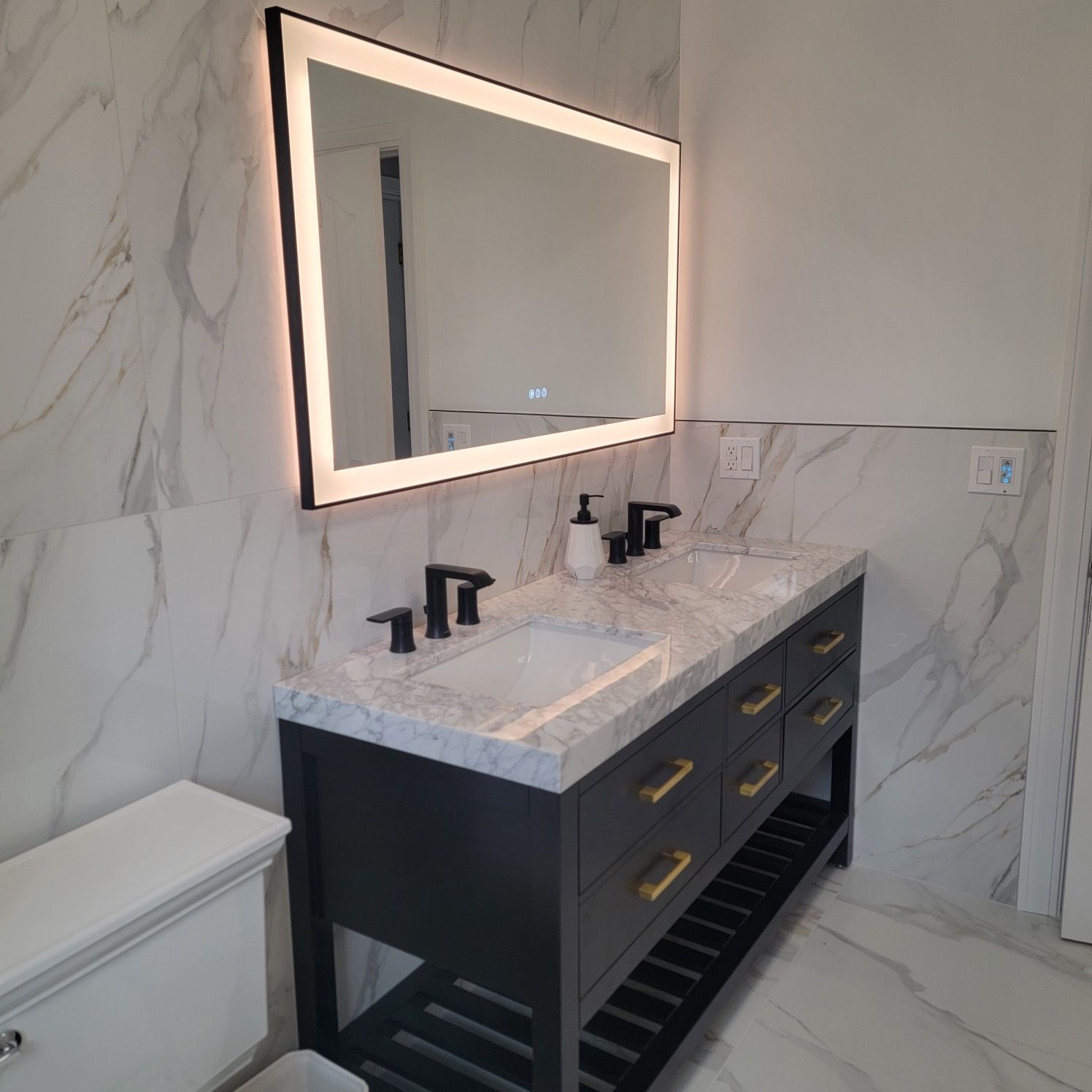 A bathroom with two sinks , a toilet and a mirror.