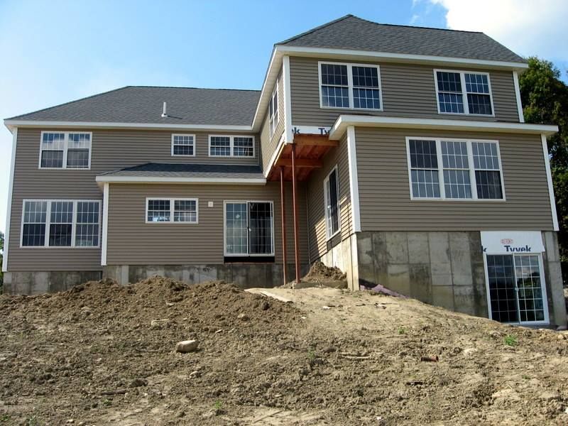 A large house with a lot of windows is sitting on top of a dirt hill