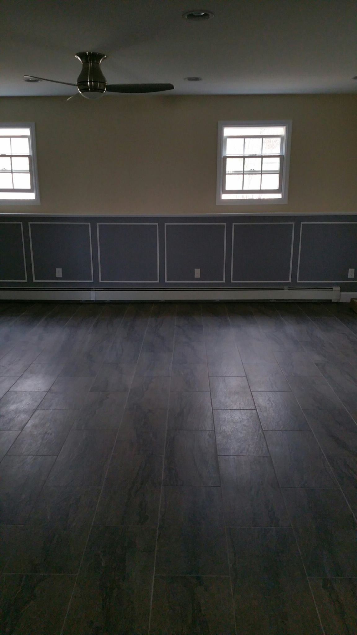 An empty room with a ceiling fan and three windows.