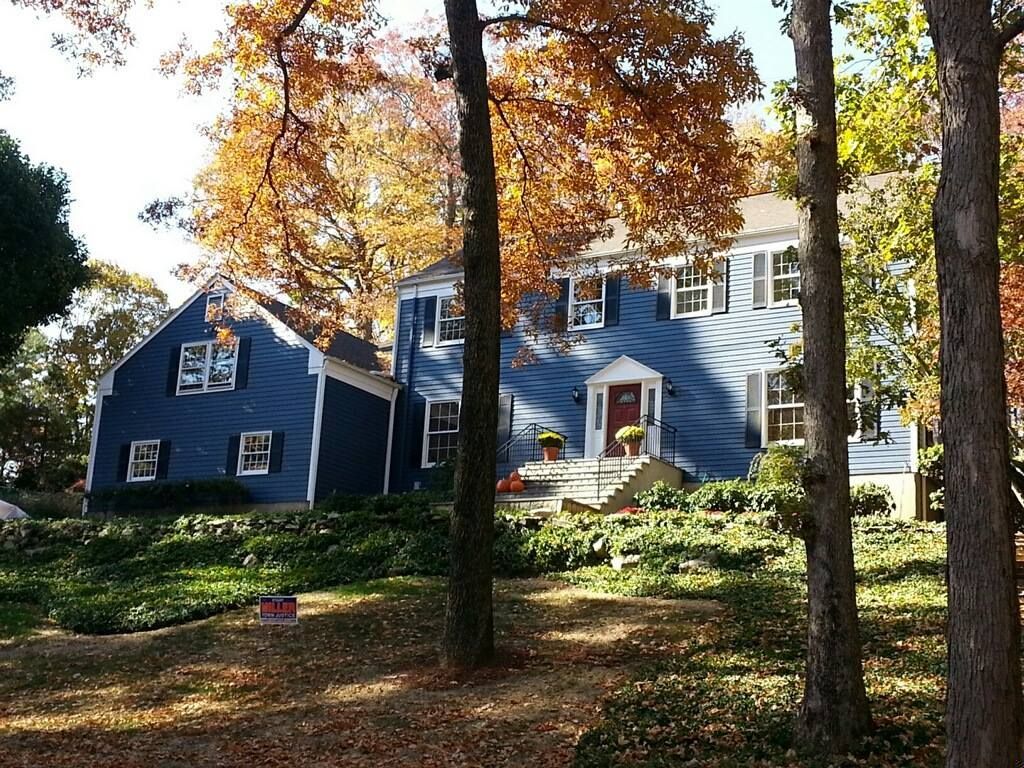 A blue house is surrounded by trees on a sunny day