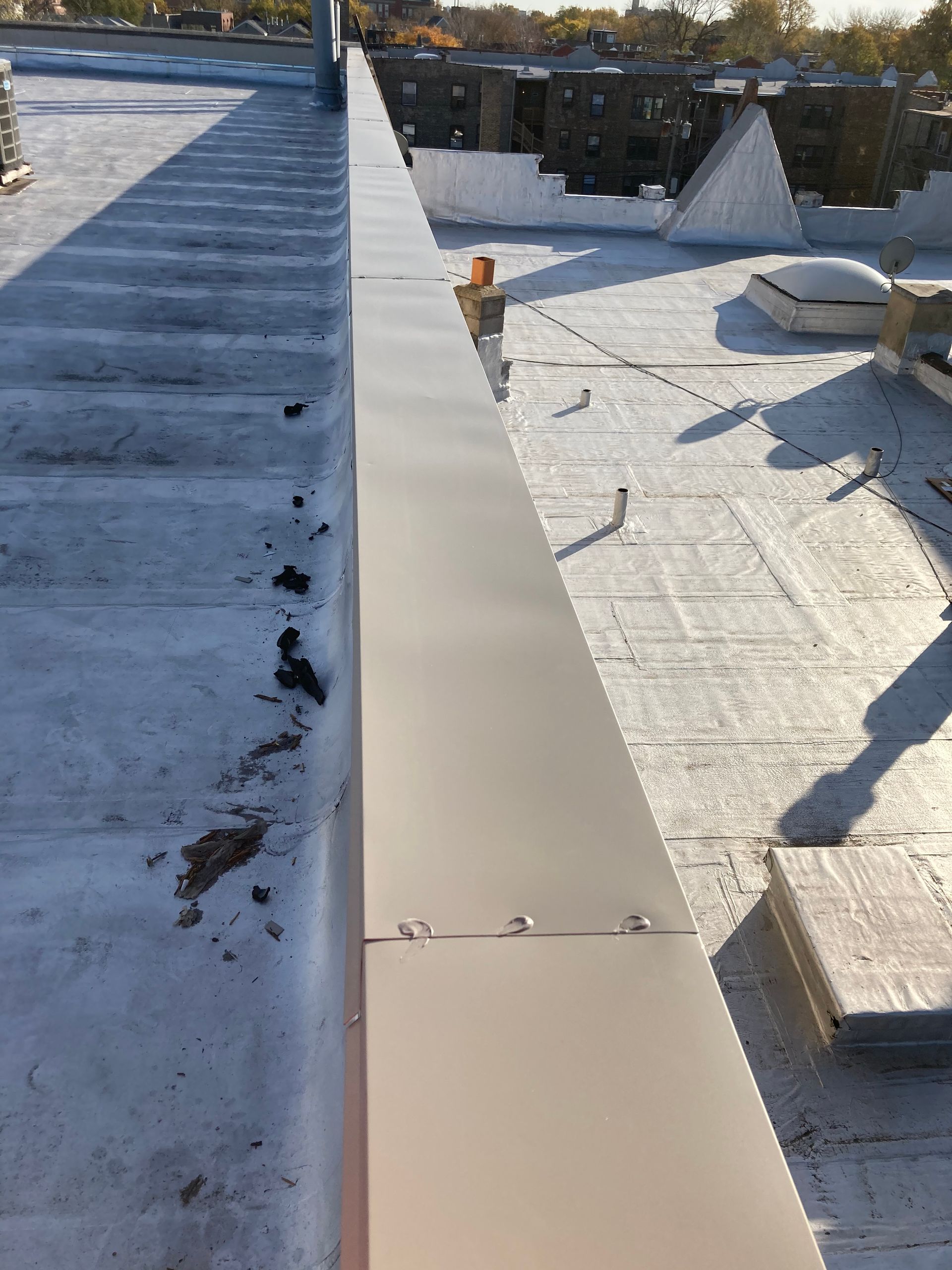 Metal flashing along the edge of a flat rooftop, secured by rivets.