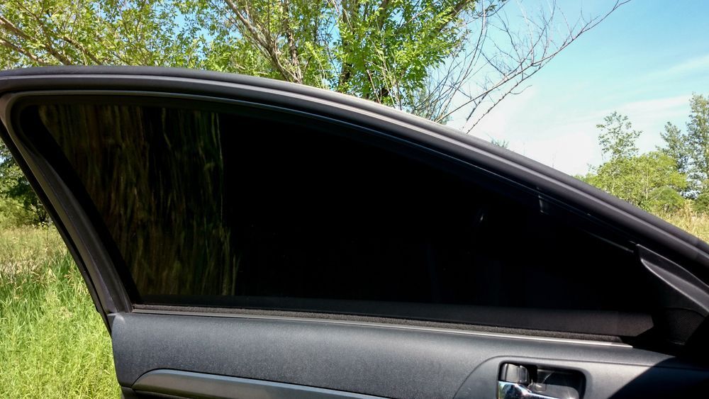 A Car With A Black Window Is Parked In A Field With Trees In The Background — Sunblitz Window Tinting In Dapto, NSW