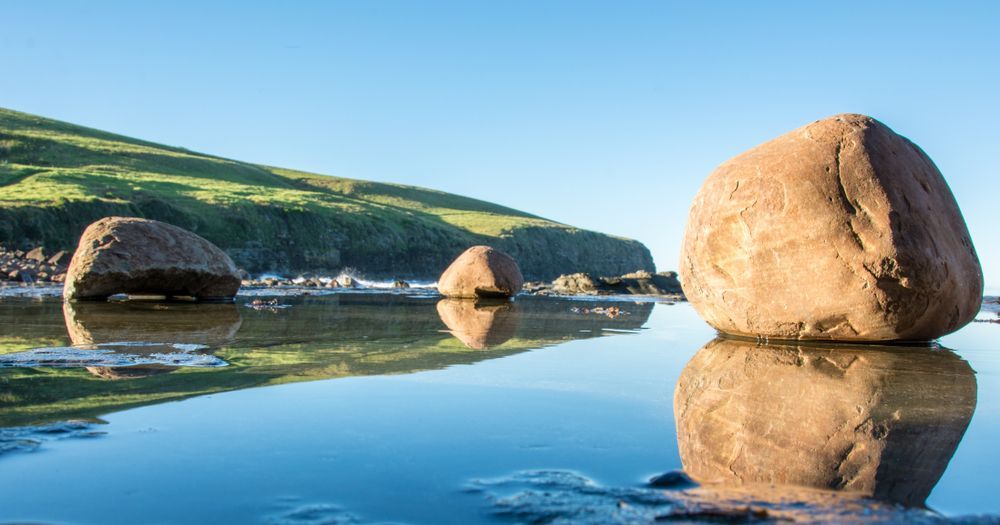 Two Large Rocks Are Sitting In The Middle Of A Lake — Sunblitz Window Tinting In Kiama, NSW