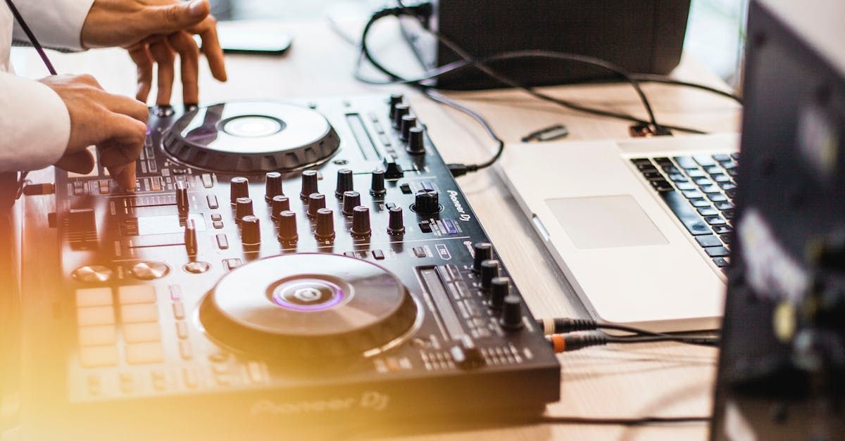 DJ mixing music with a turntable and laptop on a table. Hands operating the equipment.