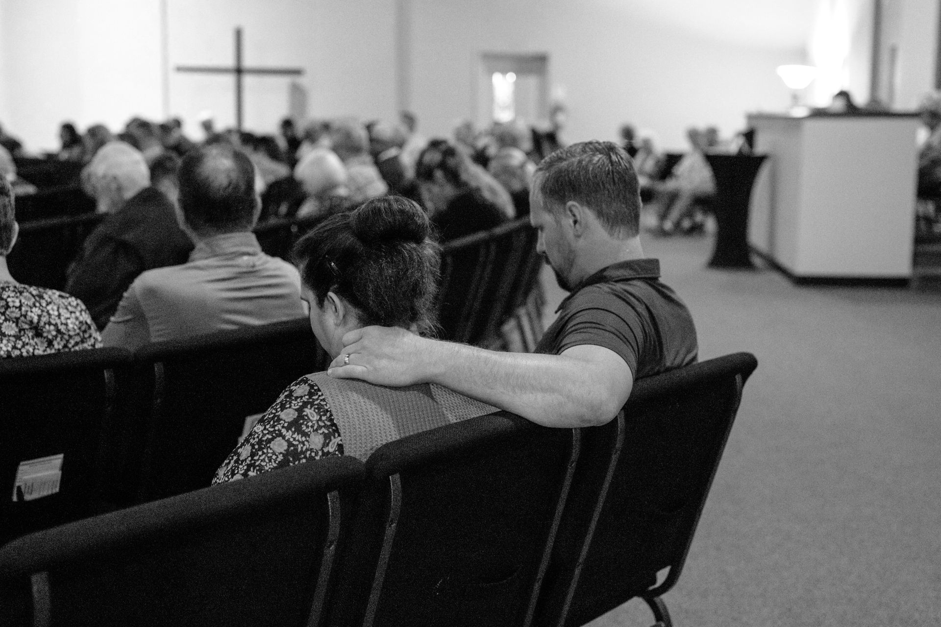 A black and white photo of a group of people standing in front of a stage.